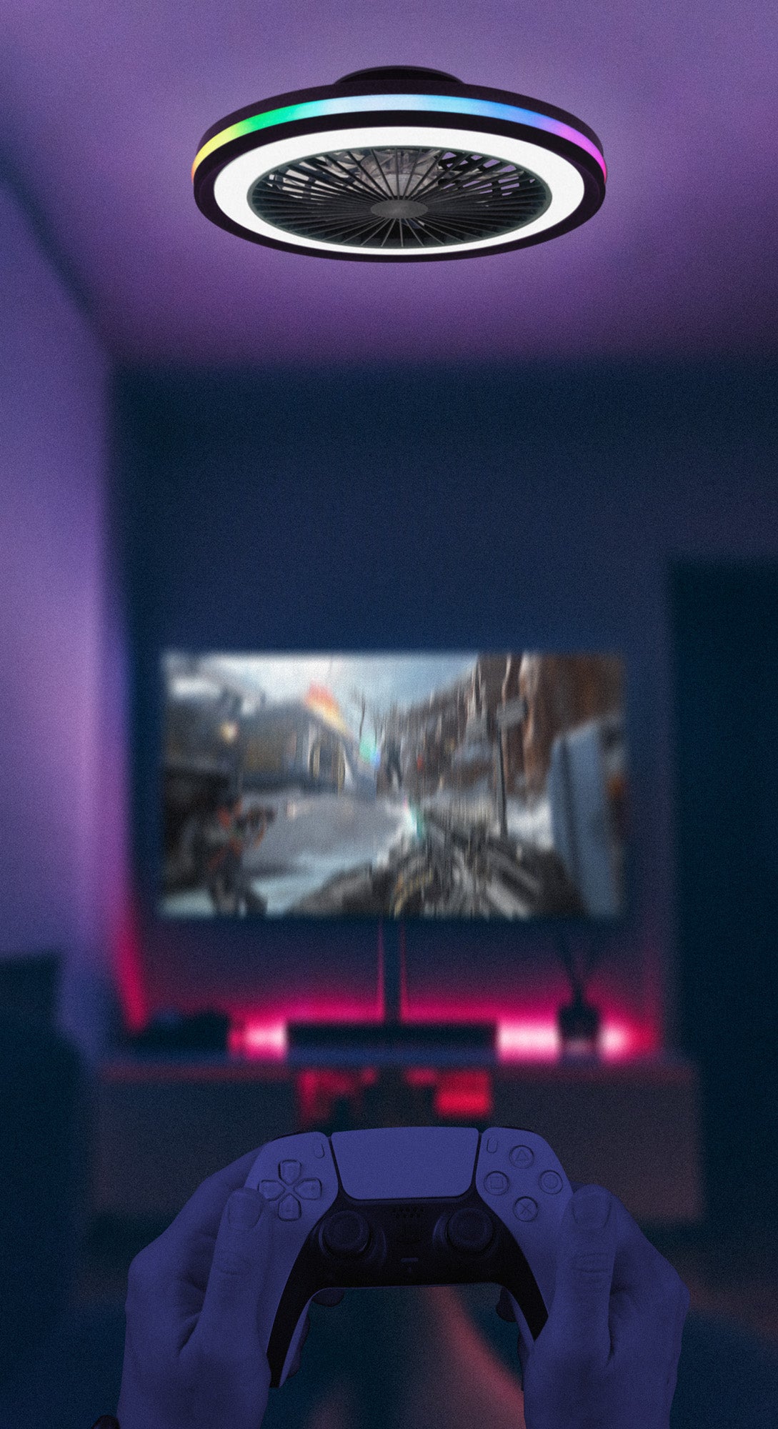 A person is holding a video game controller and facing a TV screen displaying a game set in a futuristic world. The room is dimly lit with blue and pink neon lights, enhanced by the modern Gamer Small Black Ceiling Fan from Ceiling Fans UK. The fan features a 47cm, 40W LED dimmable white/RGB ceiling light with a built-in 20W DC reversible fan, all controlled via remote for an immersive gaming experience.