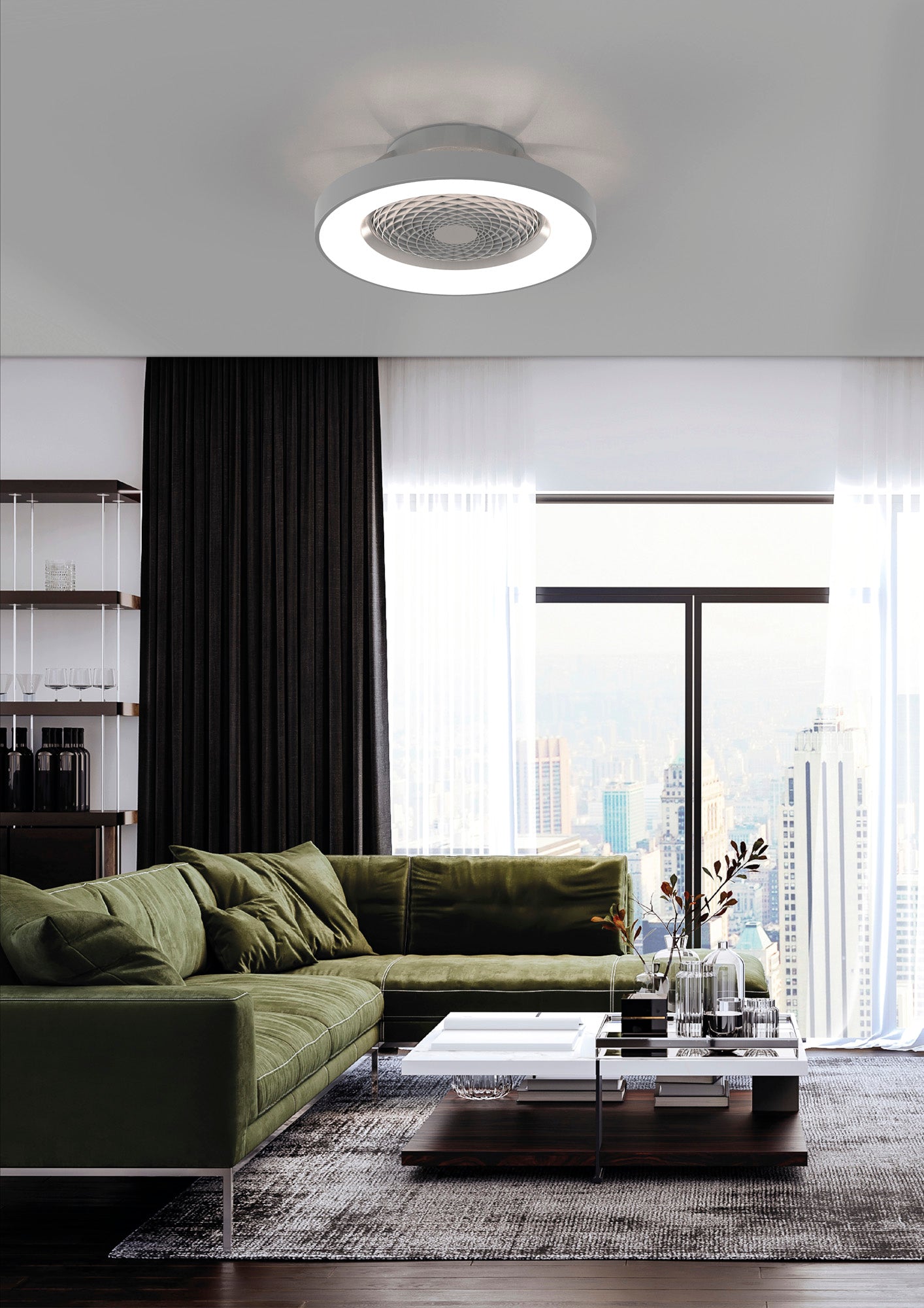 A modern living room with a green sectional sofa and glass coffee table. The furniture is complemented by a floor-to-ceiling window offering a cityscape view. The room is decorated with neutral tones and features the Ceiling Fans UK Tibet Silver Ceiling Fan with light, which includes a 65cm 70W LED dimmable ceiling light and a 35W DC reversible fan, integrated with remote, APP, and Alexa/Google Voice Control.